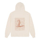 Beige hoodie with a graphic design on the back against. 