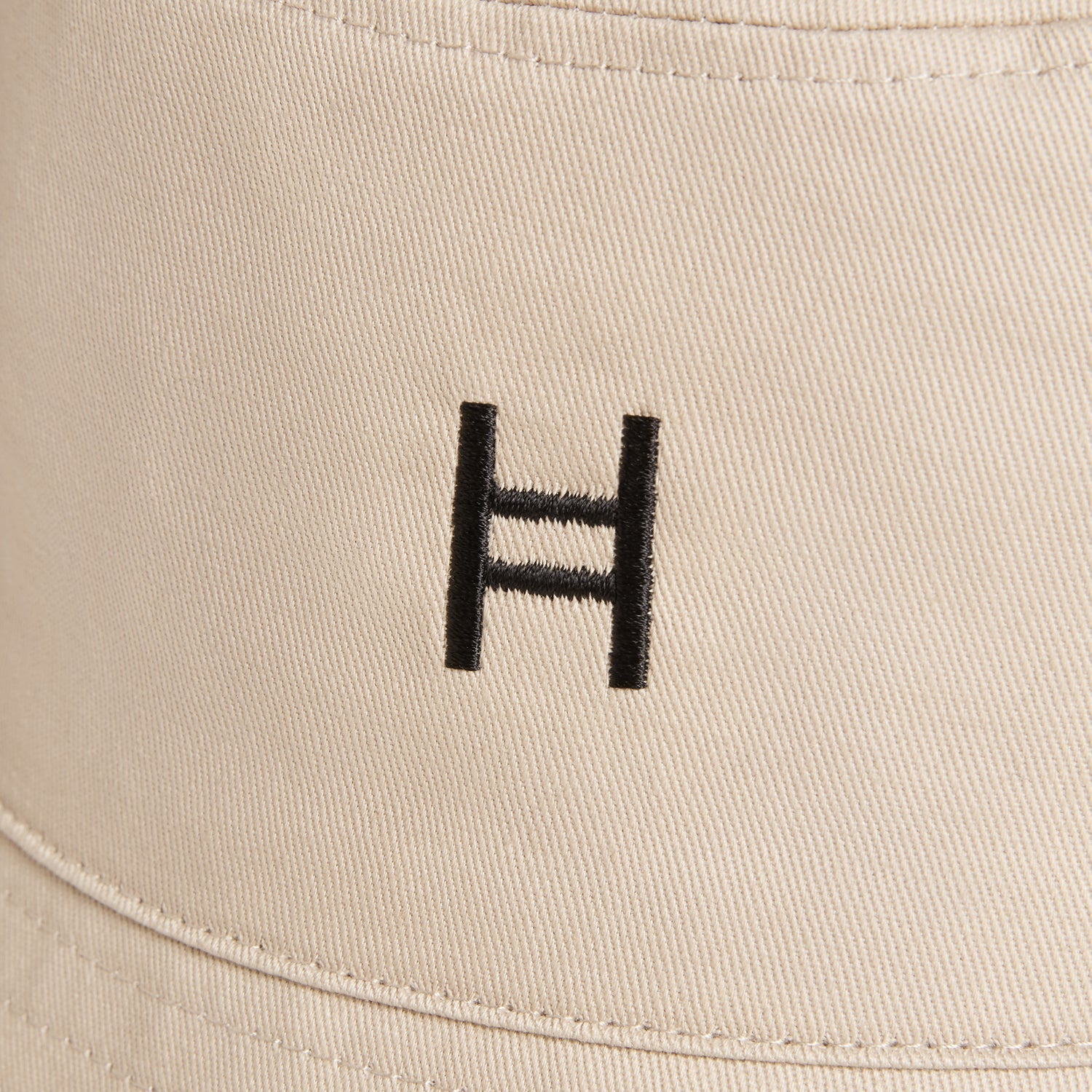 Beige cap with a black logo on a beige background