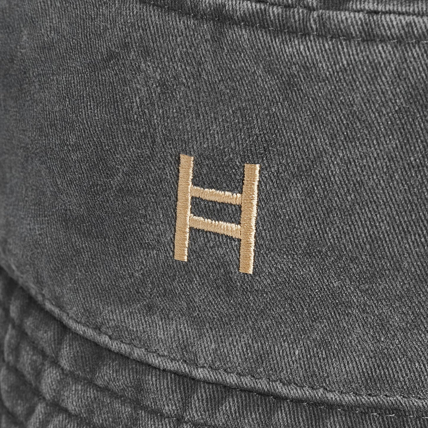 Close-up of a dark gray fabric surface with a gold logo. 