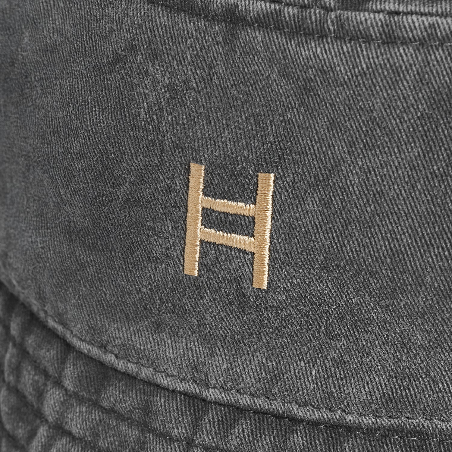 Close-up of a dark gray fabric surface with a gold logo.